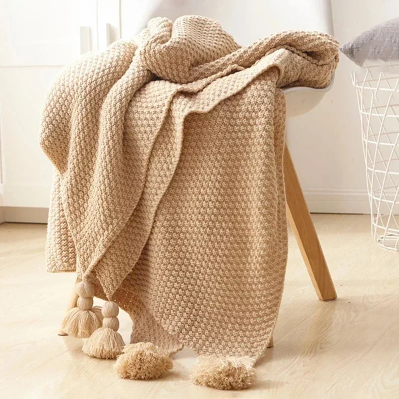 Strikket plaid i 130 × 160 cm af 100 % uld med kvaster og dekorative kugler